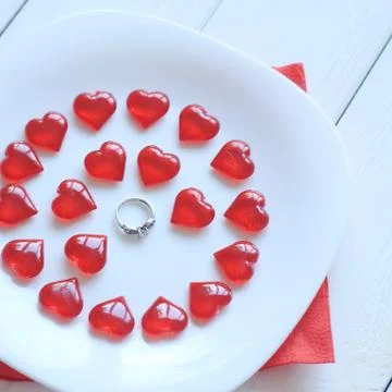 Close up.ring and red hearts on a white plate Stock Photos