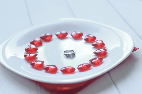 Close up.ring and red hearts on a white plate Stock Photos