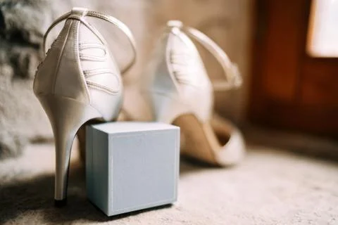 Close-up of a ring box with white bride's shoes in a room with shallow depth of Stock Photos