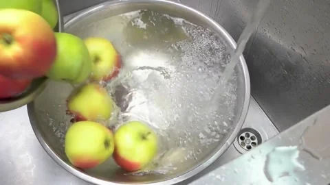 Close-up of ripe fresh apples falling into a bowl of water, creating splash.. Stock Footage 296370074