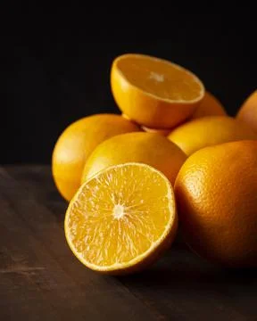 Close up of a ripe oranges cut in half on brown rustic wooden table with blac Stock Photos