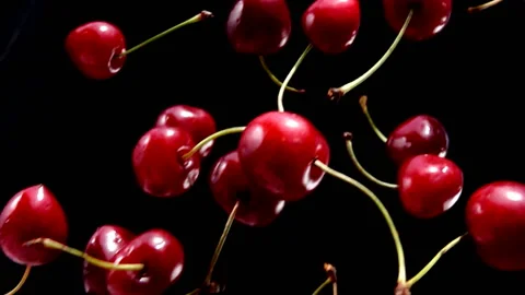 Close-up of ripe red cherry falling diagonally on a black background Stock Footage 146211873