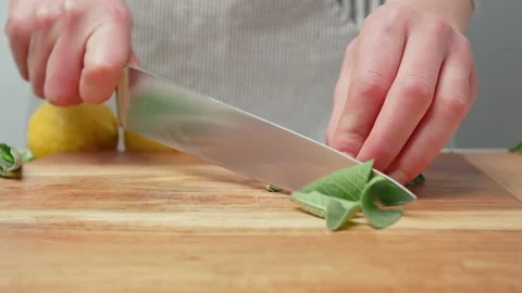 Close-up ripping and chopping fresh green Sage leaves on a cutting board in 4K. Stock Footage 145998057