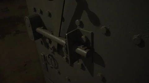 A close-up of a riveted metal door with a robust locking mechanism in low light. Stock Footage 301162339