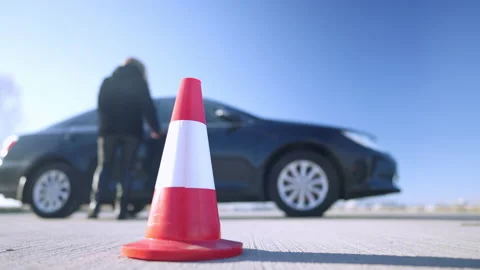 Close-up of road cone with blurred confident woman walking to car at background Stock Footage 148741369