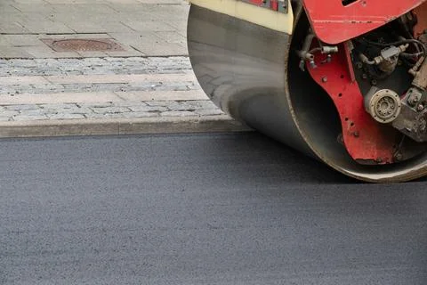 Close up of road construction asphalt roller machine at work. Stock Photos