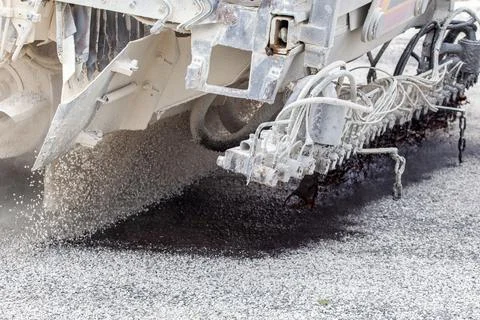 A close-up of a road construction machine applying hot bitumen and spreadin.. Photos