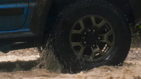 Close-up to a off road vehicle tire while driving through a puddle in Stock Footage 173201642