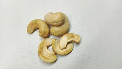 Close-up of Roasted Cashew Nut Halves and Pieces on a Grey Textured Surface Stock Photos