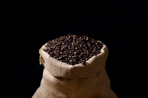 Close up roasted coffee beans in a burlap hessian sack and isolated in black.	 Stock Photos