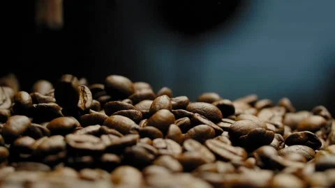 Close-up of roasted coffee beans falling down against a black background. Video stock 295673363