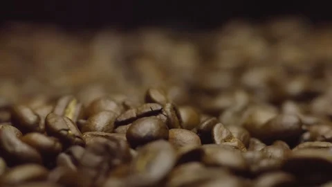 Close-up of roasted coffee beans falling down in rotation. Circular filming. Stock Footage 303634661