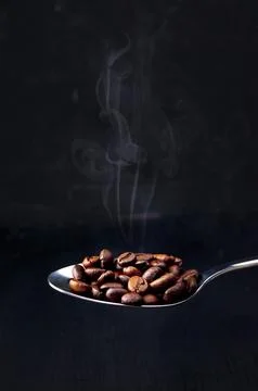 Close-up. Roasted coffee beans. Steaming coffee beans in a spoon on a black.. 스톡 사진