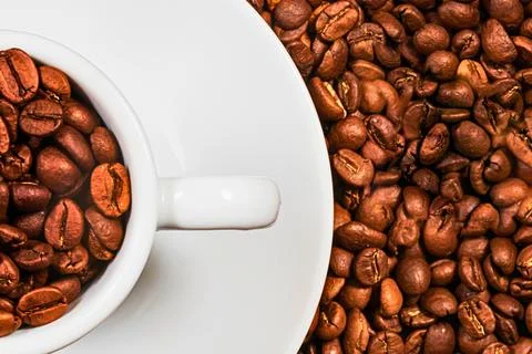 Close up of roasted coffee beans in a white cup and saucer Stock Photos