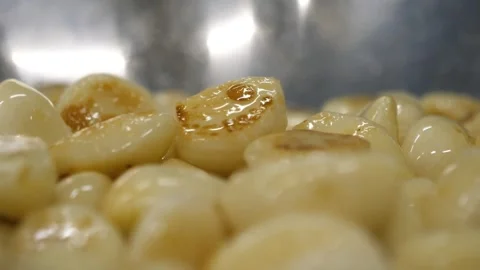Close Up of Roasted Garlic Cloves Sizzling in a Stainless Steel Pan Video stock 343028475