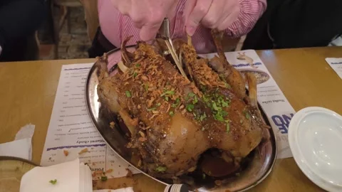 Close up of roasted goose being carved on a serving platter in a restaurant 動画素材 332728098