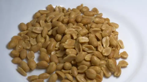 Close-up of roasted peeled peanuts rotating on a white plate, showcasing th.. 스톡 동영상 337774885