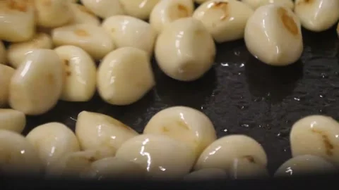 Close up of roasting peeled garlic cloves in a hot pan Video stock 343028342