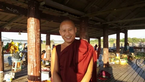 Close up of robed monk on U Bein Bridge balcony, people in background, Mandalay Видео 79624218