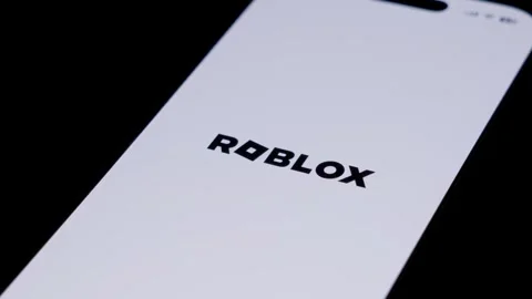 Close-up of the Roblox app startup screen on a smartphone in a dark setting Stock Footage 334059879