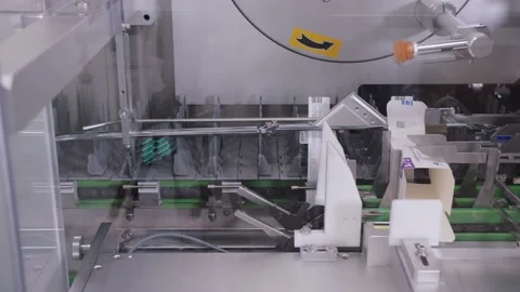 Close-up of robotic devices putting the cardboard packs for medicine to conveyor Stock Footage 200856940