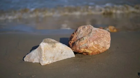 Close up on rocks on the beach with small waves  in the background Video stock 220501477