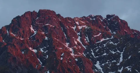 Close-up of rocky mountain terrain with snow patches, illuminated by red Stock Footage 336405875