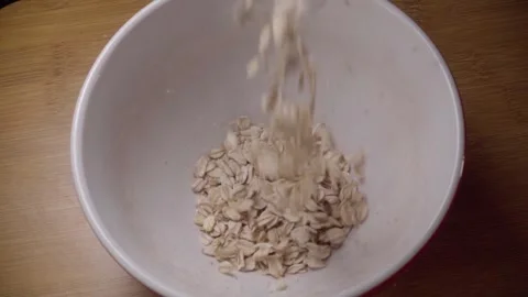 Close Up of Rolled Oats Falling Into a White Bowl During Healthy Breakfast Stock-Footage 348122826