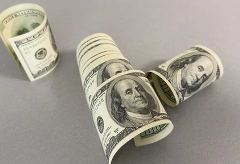 A close-up of a rolled up stack of one-dollar bills. Background with US dol.. Stock Photos