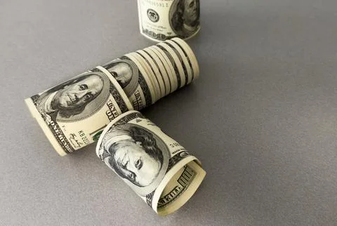 A close-up of a rolled up stack of one-dollar bills. Background with US dol.. Stock Photos
