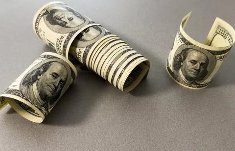 A close-up of a rolled up stack of one-dollar bills. Background with US dol.. Stock Photos