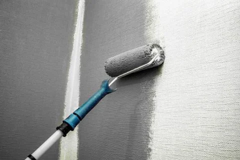 Close up roller with gray paint for painting walls. Repairs. White wall Stock Photos