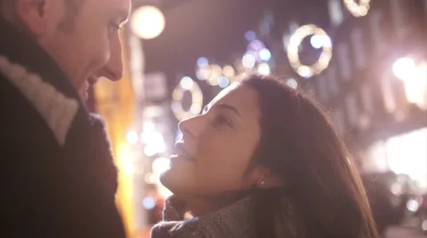 Close up of romantic couple kissing on city street at Christmas time Stock Footage