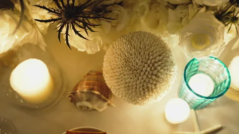 Close-up of romantic decorations made of lighted candles, shells and flowers in 库存影片 240375589