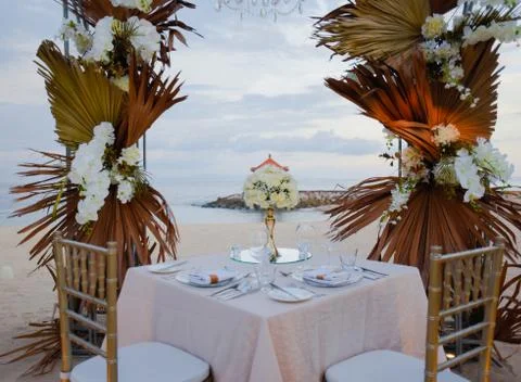 Close up to a romantic dinner setting on a beach during sunset Stock Photos