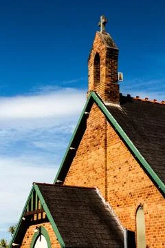 Close-Up Of The Rooftop And Cross Of A Historic Brick Church Against A Blue S Stock Photos