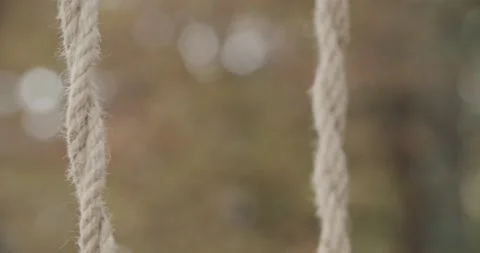 Close up of ropes of an empty swing in the middle of a desolate park in an 動画素材 140840996