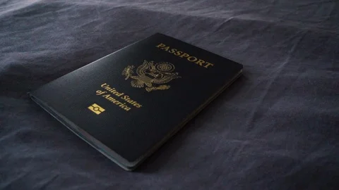 Close Up Rotate Right Around Light Illuminating American Passport on Bed Stock Footage 96044546