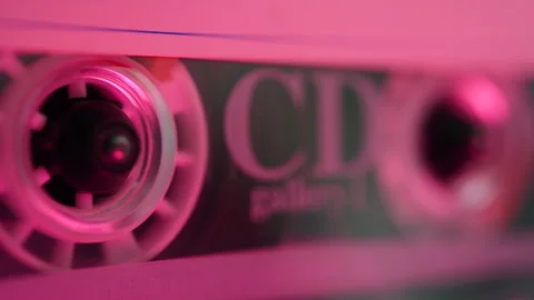 Close-up of a rotating audio cassette tape in a player with pink lighting. Stock Footage 327965658