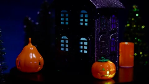 A close-up of a rotating black house surrounded by glowing, colored pumpkins Stock Footage 319393738