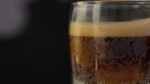 Close-Up rotating of Bubbly Dark Carbonated Beverage in a Glass with Ice Cubes Stock Footage 314833605