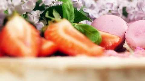 Close up of rotating cake decoration with macaroons, sliced strawberries and Video stock 99489497
