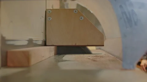 Close up of a rotating circular saw going up from a table and sawing a wooden Stock-Footage 327505771