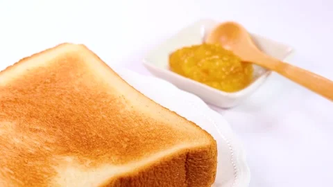 Close-up of rotating crispy toast and yuzu jam Stock Footage 325634330