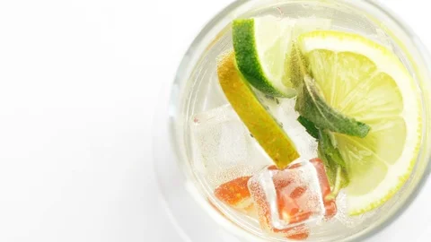 Close up of rotating fresh sliced fruit in glass with water and ice cubes. 4k ma Stock Footage 108061095
