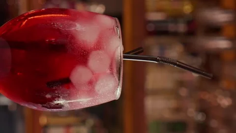 Close-up of rotating glass with Red syrup or alcohol coctail on the Bar stand Stock Footage 262484390