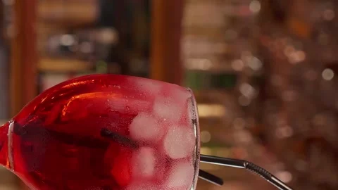 Close-up of rotating glass with Red syrup or alcohol coctail on the Bar stand Stock Footage 263154335