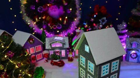 A close-up of a rotating house in front of a large decorated Christmas town Stock Footage 319895932