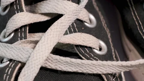Close-up of rotating pair of black used sneakers Converse with white laces. Video stock 140487460