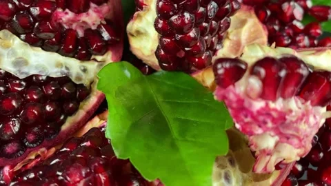 Close-up rotating pomegranate pieces ruby arils green leaf at studio Stock Footage 233096091